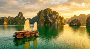 Limestone karsts rising from emerald water in Halong Bay at golden hour, traditional junk boat in foreground, warm sunse