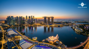 Aerial view of Singapore's Marina Bay skyline at dusk with vibrant city lights reflecting on calm water, wide-angle shot