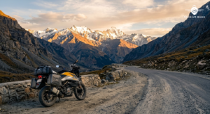 Adventure motorcycle parked on Manali-Leh highway with snow-capped Himalayan peaks in background, golden hour light, wid