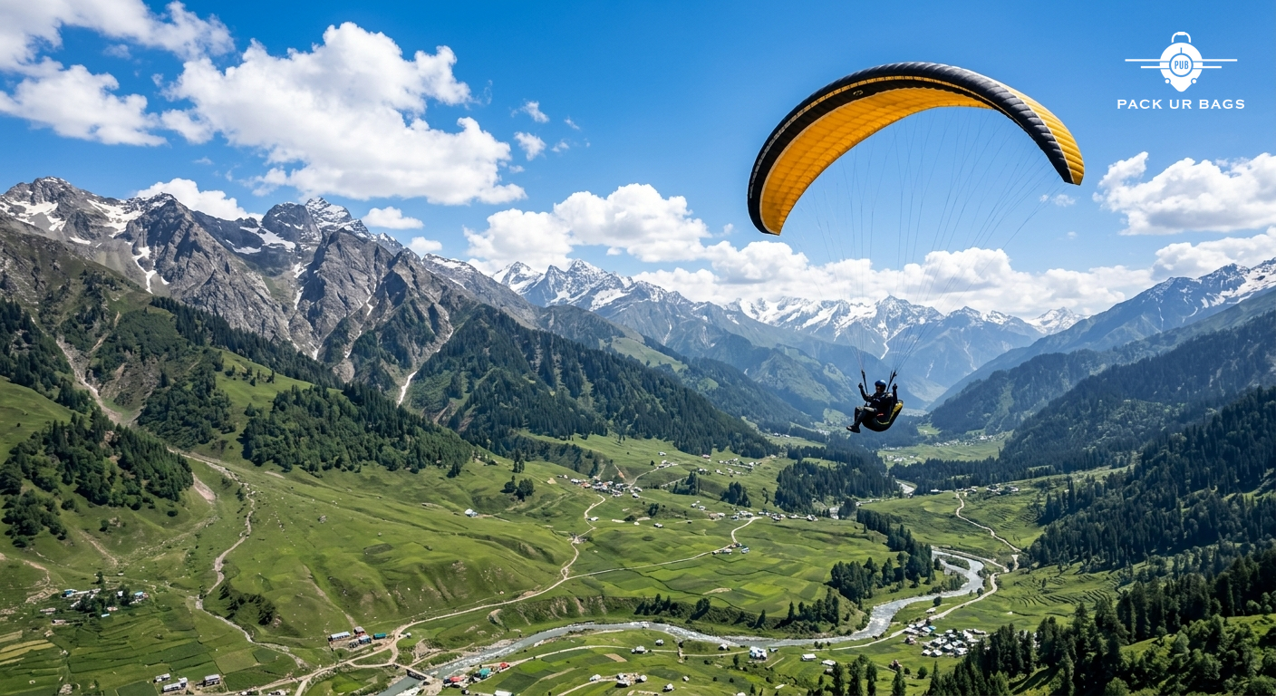 Paraglider soaring above Solang Valley with green meadows and rocky peaks below, bright blue sky, adventure travel photo